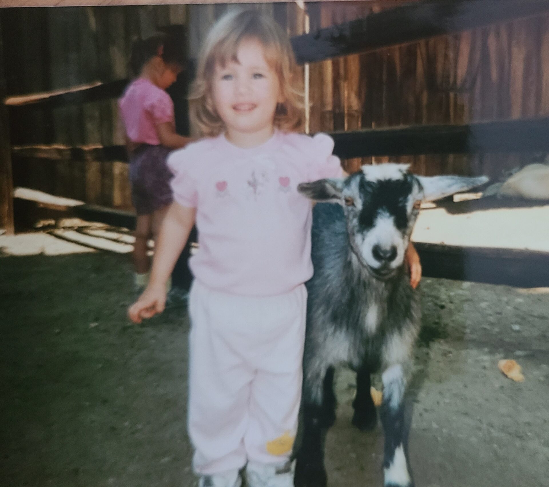 Little girl with her arm around a goat