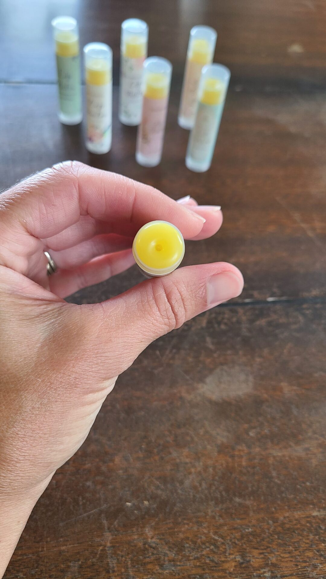 Homemade beeswax lip balm held in a hand with other lip balms behind it.
