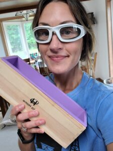 Woman with safety goggles holding a soap mold