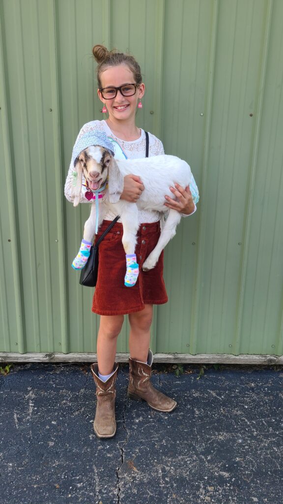 Girl and baby goat dressed up
