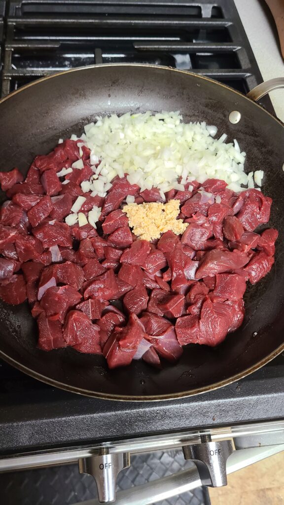 Venison, onions, and garlic on stove top