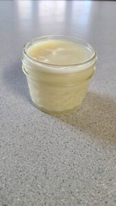 Homemade solid goat tallow balm in a glass jar.
