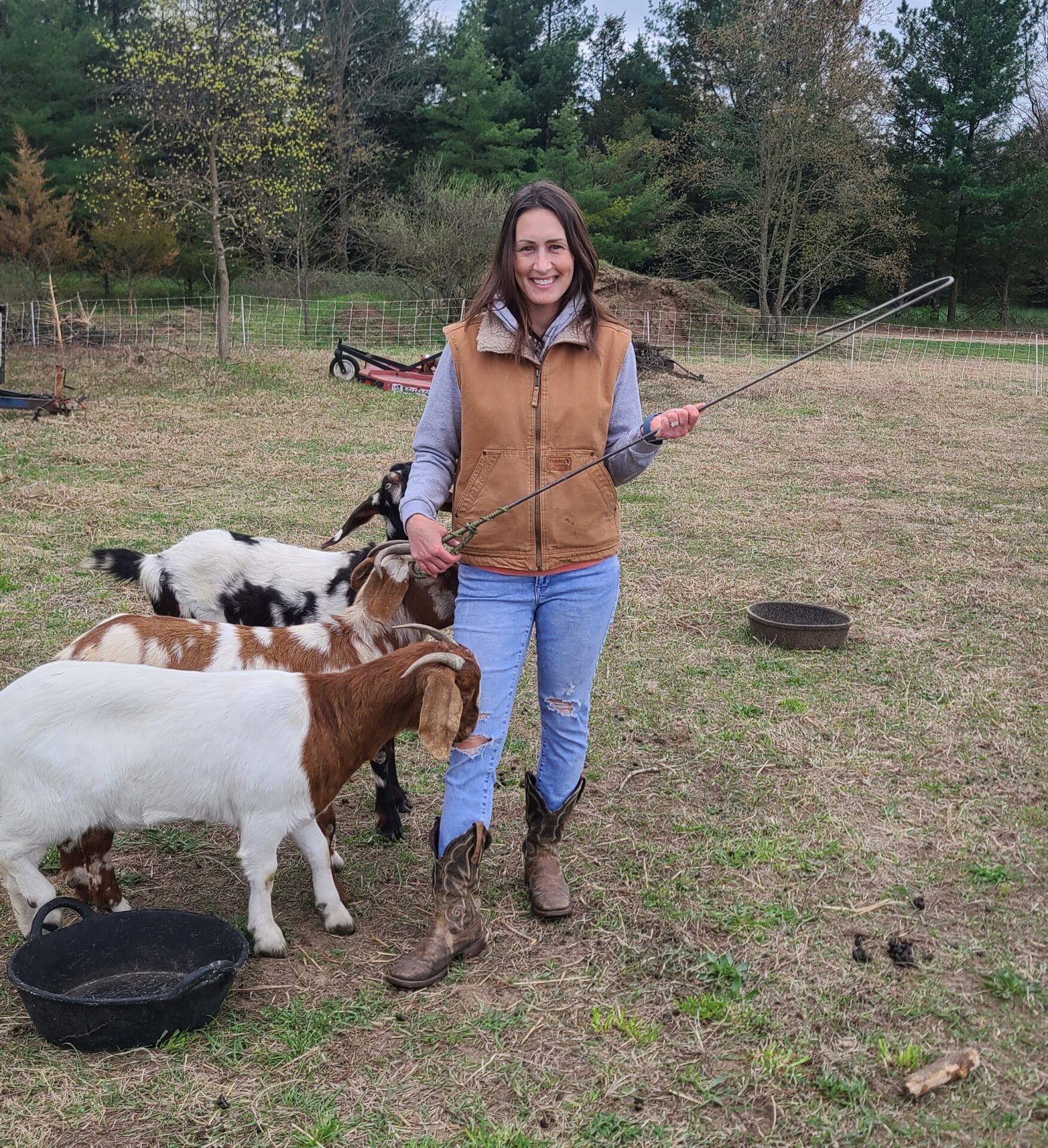 Woman holding a leg hook standing my three goats