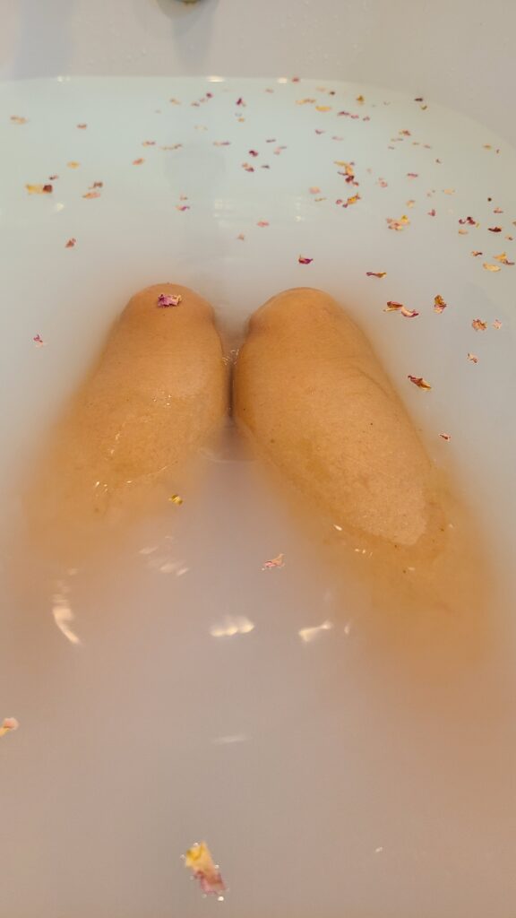 Woman's legs in a milk bath with rose petals