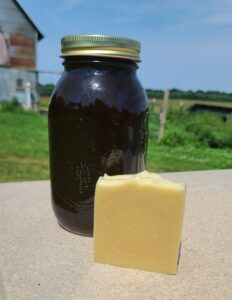 Mason jar containing jewelweed infused olive oil with a bar of soap in front of it.