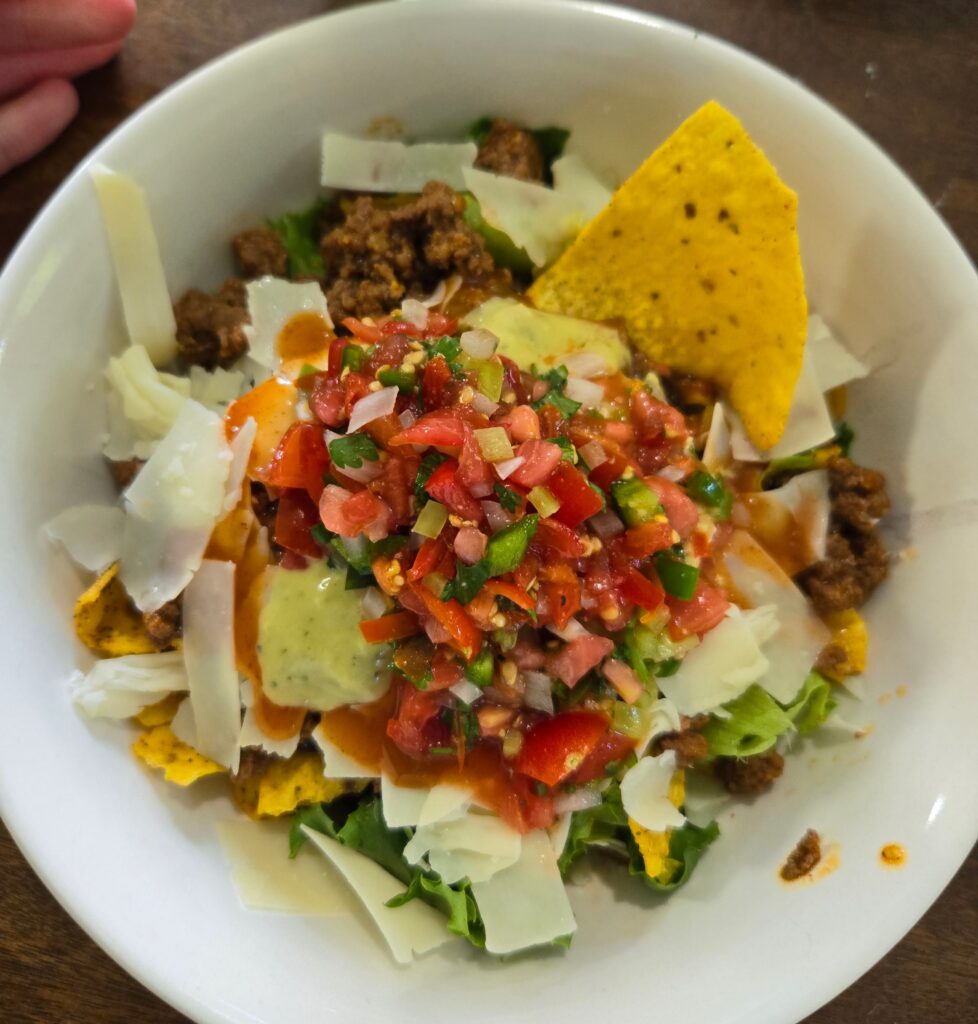 Fresh garden salsa on top of a taco salad in a white bowl.