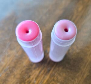 Homemade tallow lip balm in two different shades, pink and purple