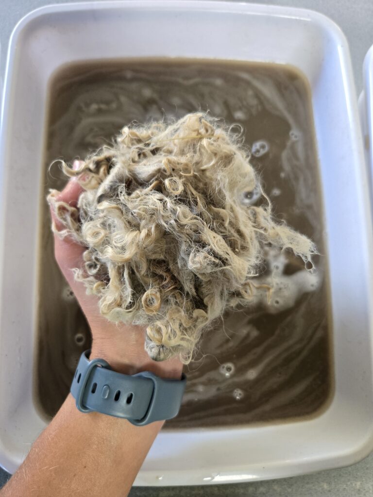 A ball of mohair being squeezed out by a person's hand.