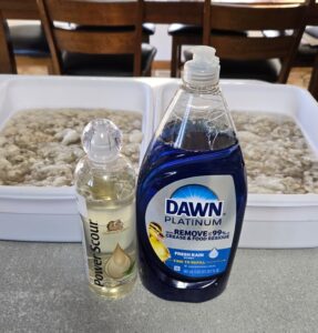 Two totes of mohair fleece being soaked with Power Scour and Dawn dish soap in front of them.
