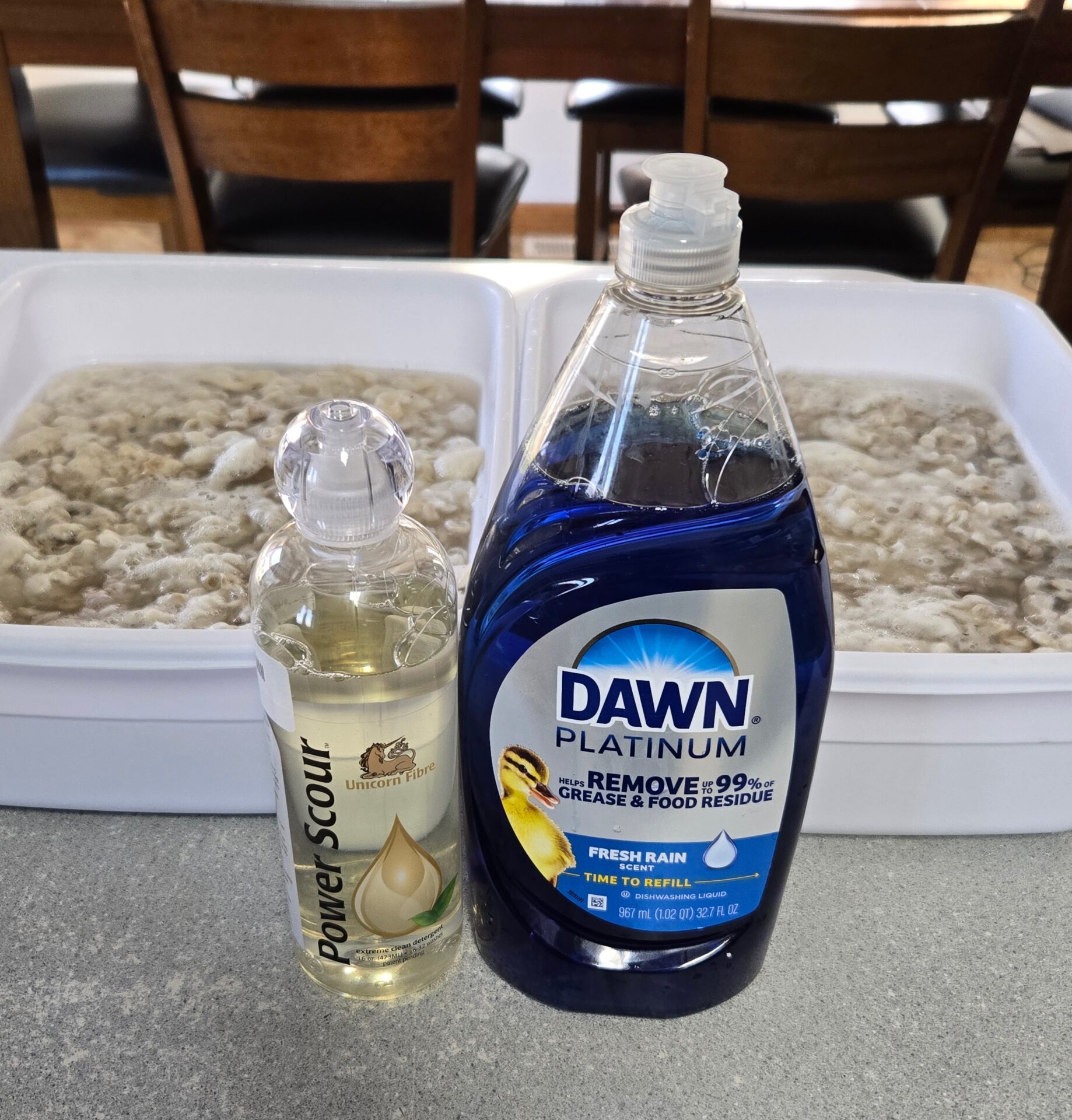 Two totes of mohair fleece being soaked with Power Scour and Dawn dish soap in front of them.