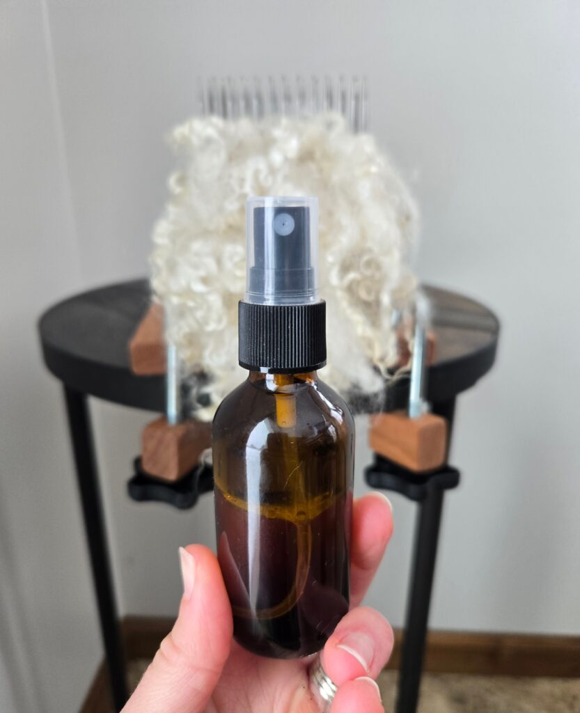 Spray bottle in front of a wool comb with mohair on it.