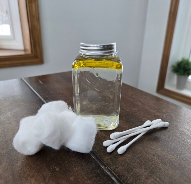 Homemade makeup remover on a table with cotton balls and cotton swabs