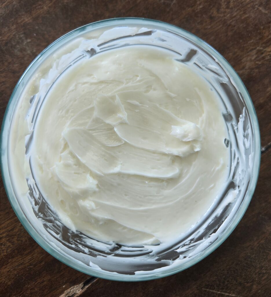 Making butter with goat milk in a glass bowl.