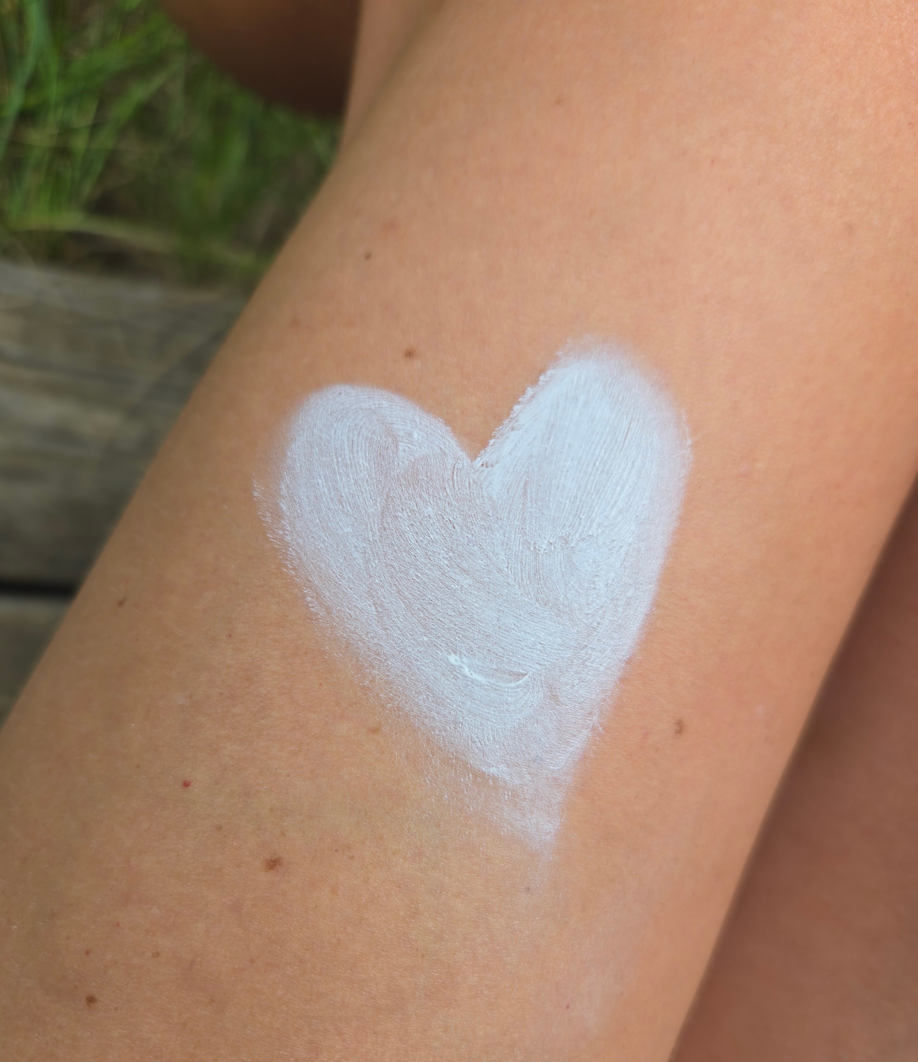 Woman's leg with a heart in sunscreen.