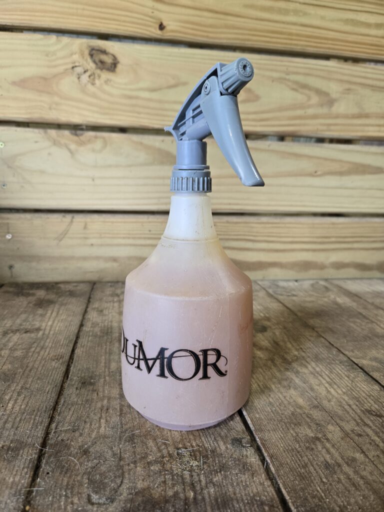 A spray bottle containing homemade fly spray for goats and horses.
