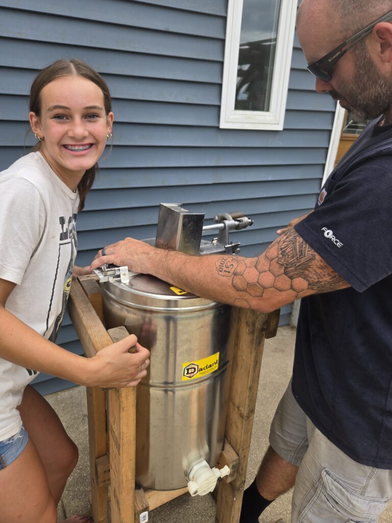 A father and daughter using a honey extractor.