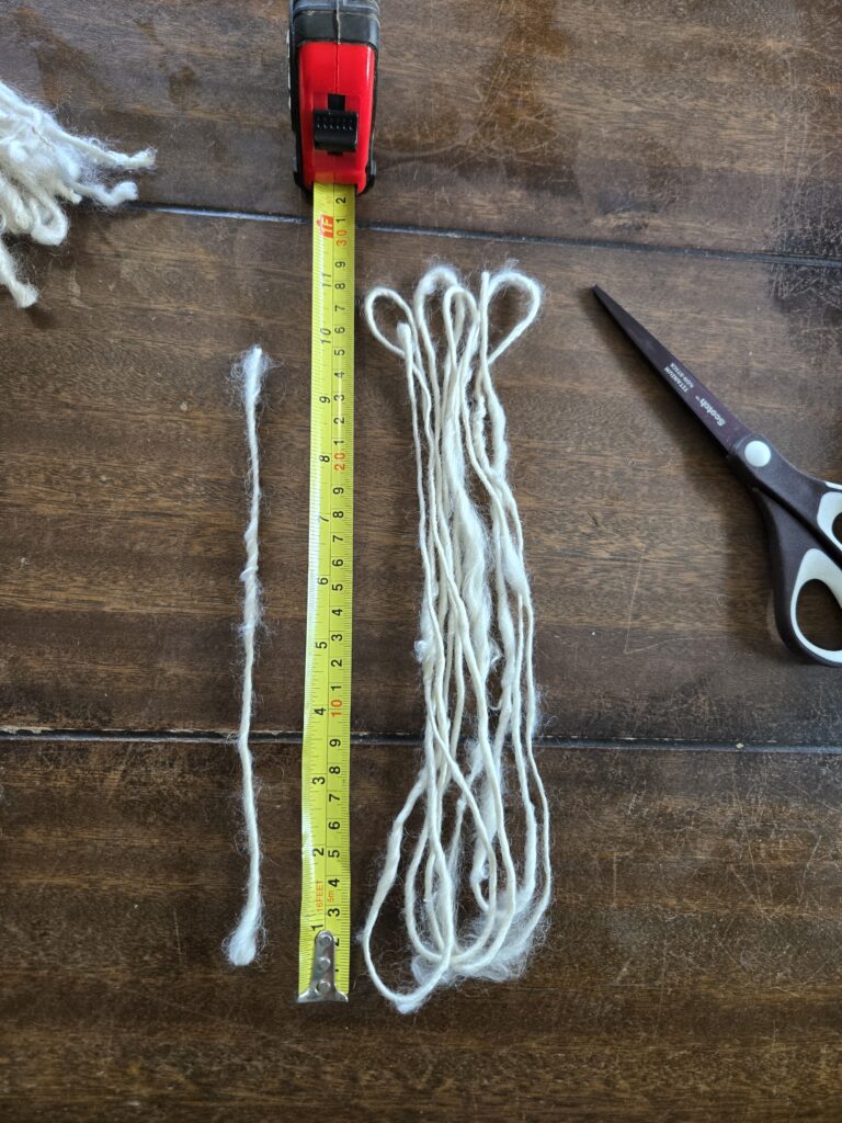 White yarn laying next to a tape measure.