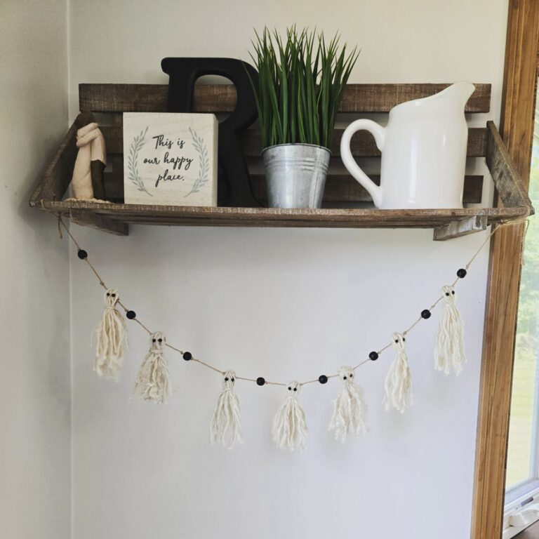 A handmade rustic yarn ghost garland hanging from a shelf