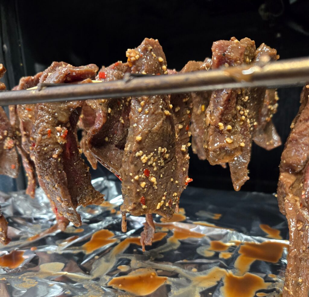 Meat hanging from toothpicks in the oven.