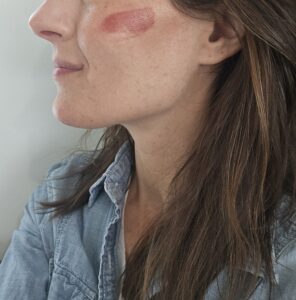 Tallow cream blush on a woman's cheek,