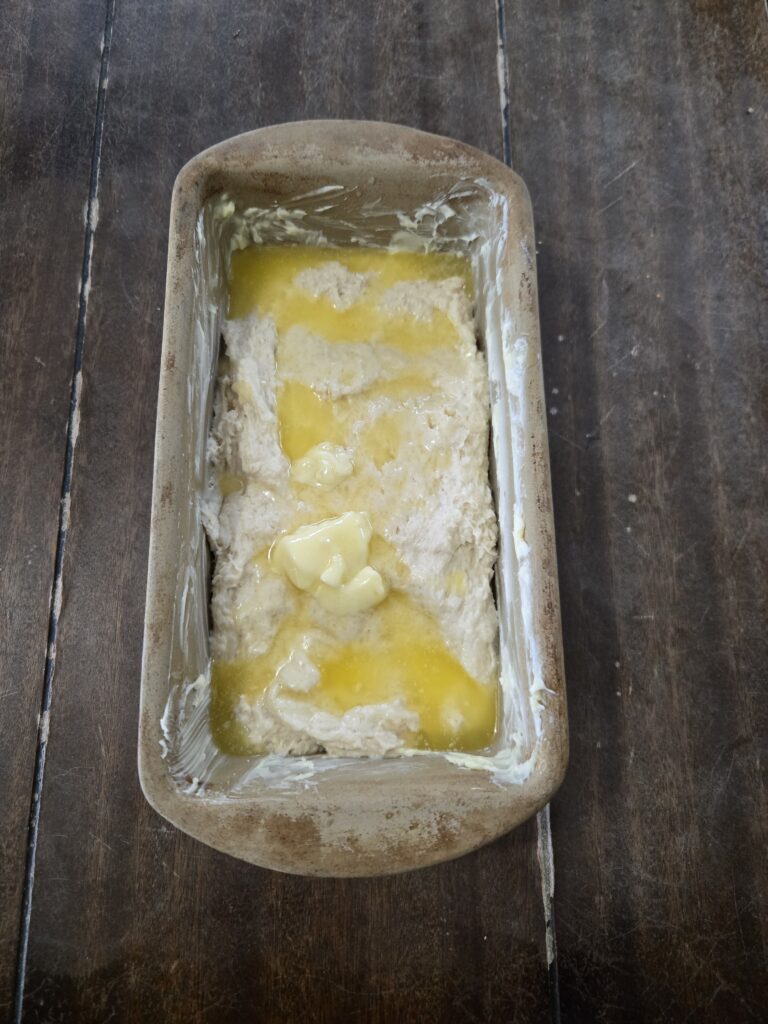 Bread dough in a pan with butter