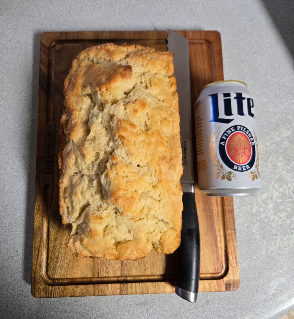 Honey beer bread with a can of beer and a knife.