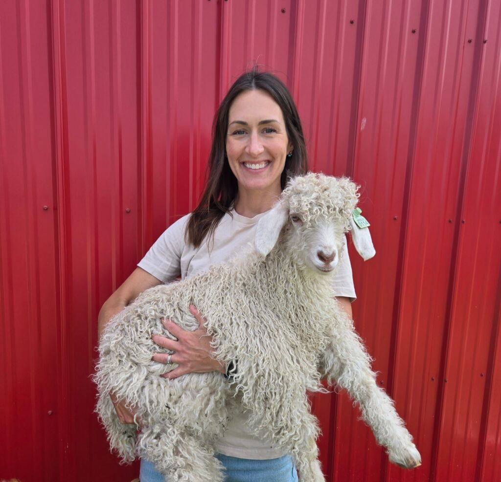 A woman holding a young Angora Goat