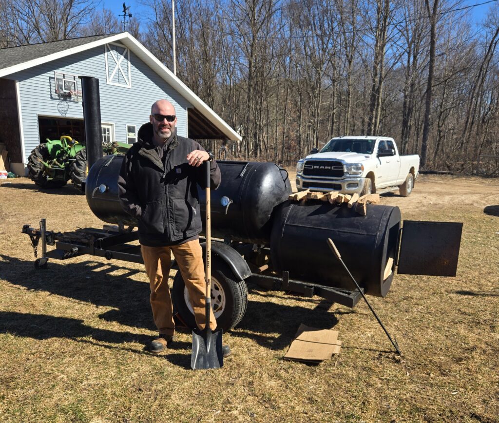 A man with a homemade offset smoker.