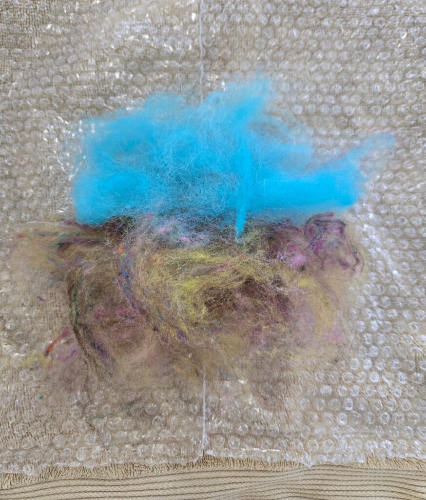 Fiber laid out to make a wet-felted coaster