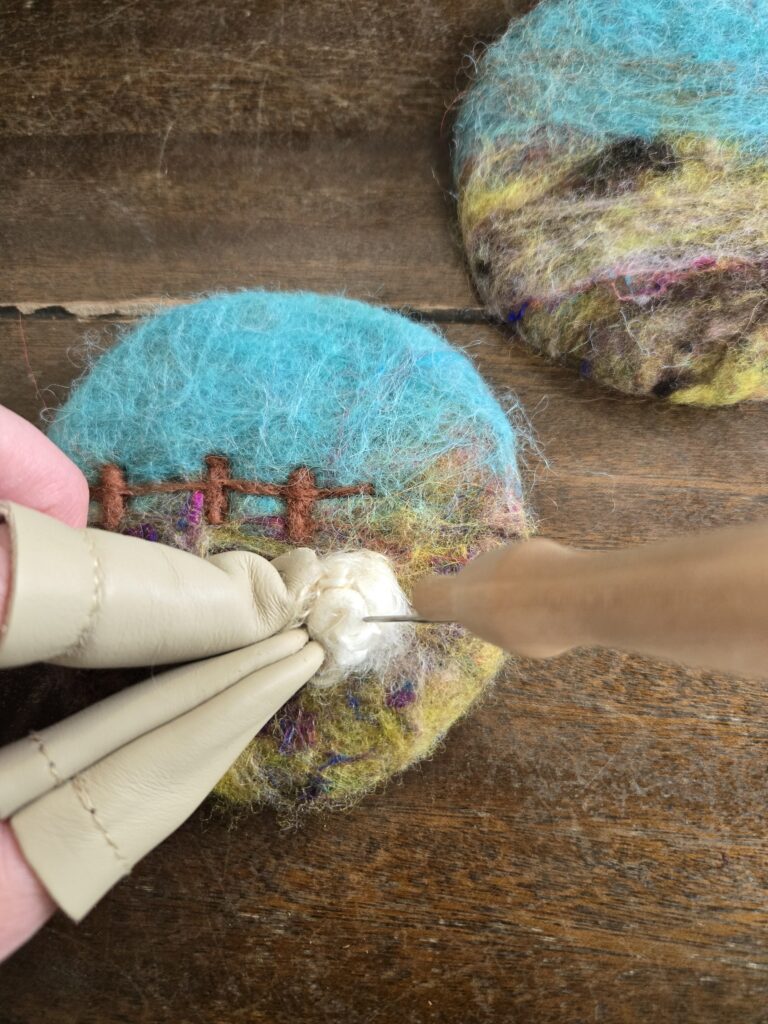 Needle-felting a design on the wet-felted coaster.