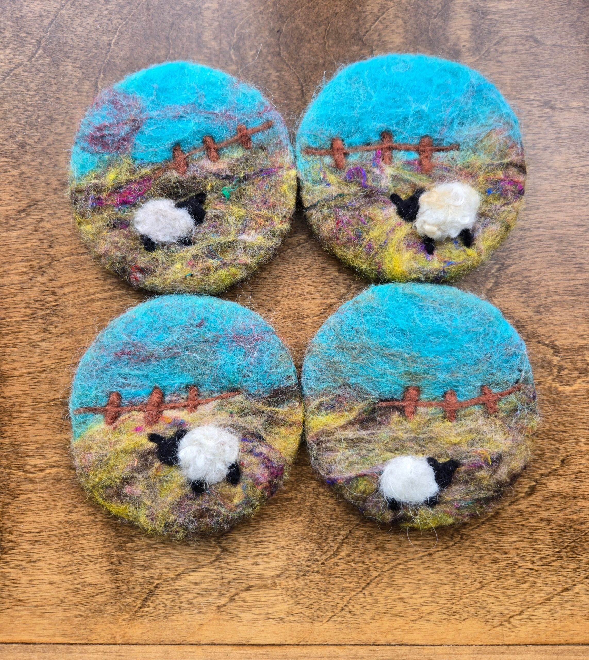 A set of 4 wet-felted coasters with sheep on them.