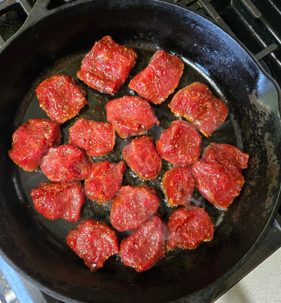 Searing side one of the goat loin medallions 