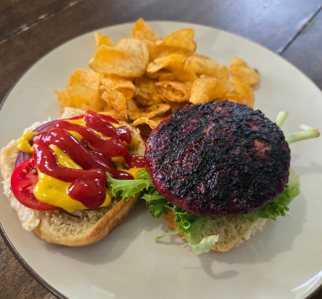 Goat burger recipe on a plate with chips and condiments